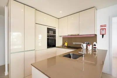 a kitchen with white cabinets and a sink at Apartamento Porlamar in Quarteira
