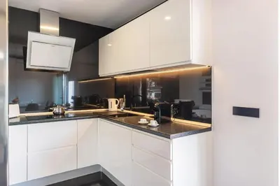 a kitchen with white cabinets and black counter tops at Vilamoura Premium Apartment With Pool by Homing in Vilamoura