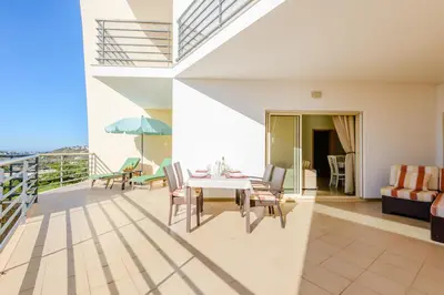 a living room with a couch and a balcony at BnB Homes Ocean view Apartment with huge sunny Terrace, 2 Swimming pools & Tennis court in Albufeira