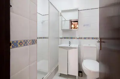 a white bathroom with a toilet and a sink at Vila Caracol in Guia