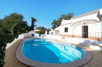 a swimming pool in front of a white house at Vila Caracol in Guia