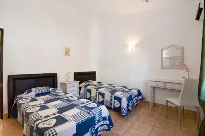 two beds in a room with a table and a desk at Vila Filipa in Guia