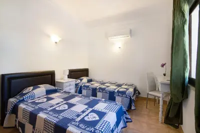 a room with two beds and a table and a desk at Vila Filipa in Guia