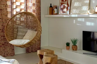 a room with a rattan chair next to a tv at Casa do Pátio-Two Private Pools Villa- Rooftop & Panoramic Pool by DreamvillasAlbufeira in Albufeira