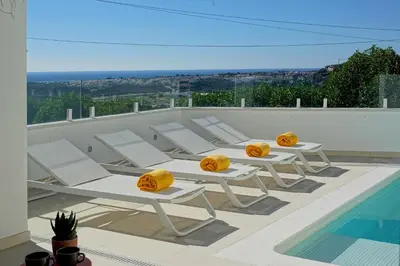 a row of white lounge chairs sitting next to a swimming pool at Casa do Pátio-Two Private Pools Villa- Rooftop & Panoramic Pool by DreamvillasAlbufeira in Albufeira