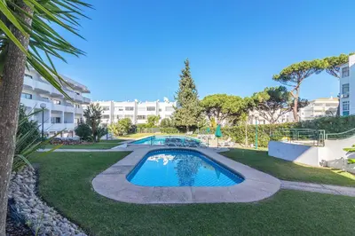 a swimming pool in a park with a building in the background at Vilamoura Cosy 2 with Pool by Homing in Vilamoura