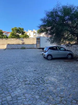 a small car parked in a stone parking lot at The Strip Oura apartment in Albufeira