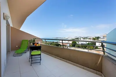 a balcony with green chairs and a table with a view at Albufeira - Apartment - Sleeps 4 - Pool - Seaside in Albufeira