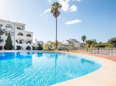 a swimming pool with a palm tree in front of a building at Apartment Melbourne 2 by Algarve Vacation in Albufeira