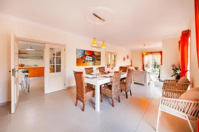 a dining room and living room with a table and chairs at Villa Dalia by Algarve Vacation in Almancil