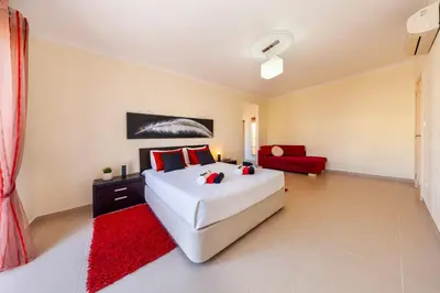 a bedroom with a white bed and a red couch at Villa Dalia by Algarve Vacation in Almancil