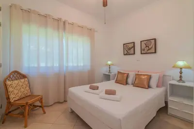 a bedroom with a large white bed and a chair at Vilamoura - M M GARDEN - Magnifico T2 in Vilamoura