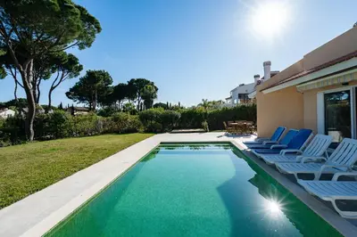 a swimming pool with lounge chairs next to a house at Villa Mianas by SAPvillas in Vilamoura