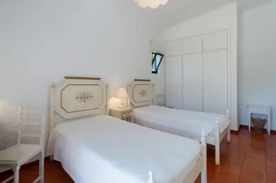 a bedroom with two beds and a chair in it at Villa Serendipity by SAPvillas in Vilamoura