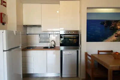 a kitchen with white cabinets and a table and a refrigerator at Marina Mar Marina by SAPvillas in Vilamoura