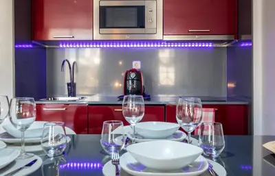 a kitchen with red cabinets and a table with wine glasses at #070 T0 Edifício Albufeira by Home Holidays in Albufeira