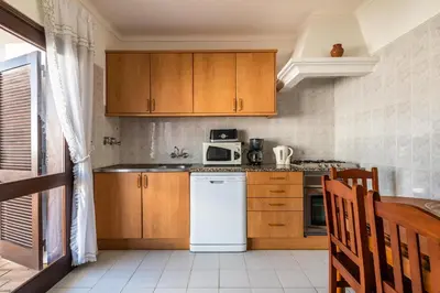a kitchen with wooden cabinets and a white refrigerator at Villa Canto II - 500m from the Beach - Private Swimming Pool - Wi Fi in Guia
