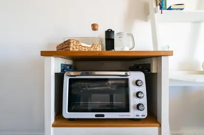 a microwave sitting on a shelf in a kitchen at Albufeira Beach Apartment in Guia