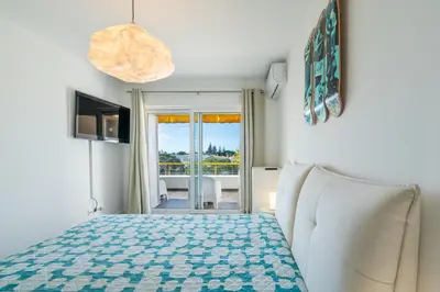 a bedroom with a bed and a couch and a window at Albufeira Beach Apartment in Guia
