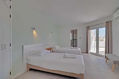two beds in a white room with a balcony at Villux - Vila Enar-6 quartos, ideal para familias in Albufeira