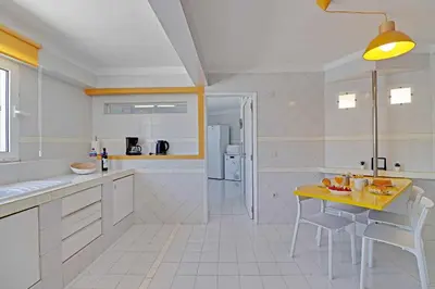 a white kitchen with a yellow table and chairs at Villux - Vila Enar-6 quartos, ideal para familias in Albufeira