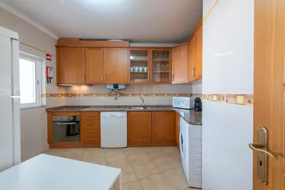 a kitchen with wooden cabinets and a white refrigerator at Apartamento Monarquia - T3 Quarteira in Quarteira