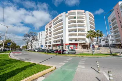 a large white building with cars parked in front of it at Apartamento Monarquia - T3 Quarteira in Quarteira