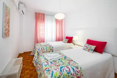 two beds in a white room with red accents at Apartamento Vista Mar T2 in Quarteira