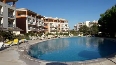 a swimming pool in front of a building at Luxurious first floor apartment with balconies overlooking pool and gardens. in Albufeira