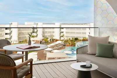 a couch with pillows on a balcony with a pool at W Algarve in Albufeira