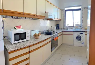 a kitchen with a microwave and a washer and dryer at Apartamentos Ninho das Gaivotas in Albufeira