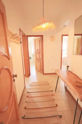 a hallway with a table and some rugs on the floor at Apartamentos Ninho das Gaivotas in Albufeira