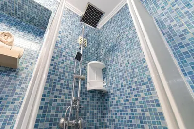 a blue tiled bathroom with a shower in it at Sea & Sun OldTown in Albufeira