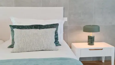 a bed with a green pillow and a lamp on a table at Villa Sadler- Clever Details, Central Vilamoura, Sleeps 6, luxury, walking distance in Vilamoura