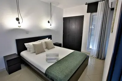 a bedroom with a large white bed with a green blanket at Go4Portugal - Lagoa - Apartment 3 min from beach with airco and balcony in Quarteira
