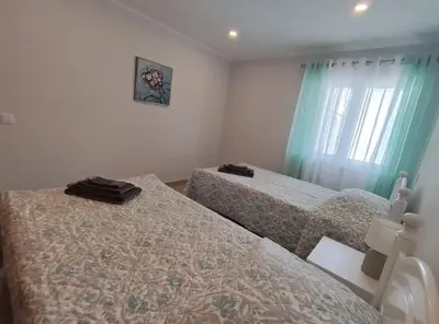 a bedroom with two beds and a window with green curtains at Alojamento King´s Village in Albufeira