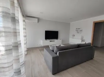 a living room with a couch and a flat screen tv at Alojamento King´s Village in Albufeira