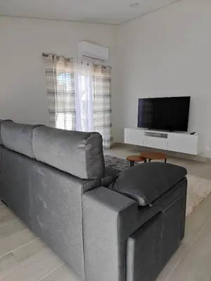 a living room with a couch and a flat screen tv at Alojamento King´s Village in Albufeira