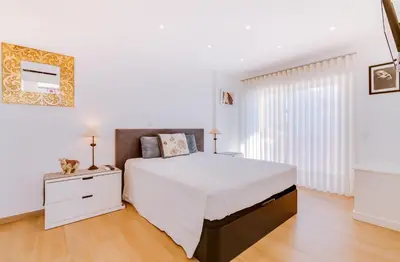 a white bedroom with a large bed and a dresser at AL - Ocean Wide View in Quarteira