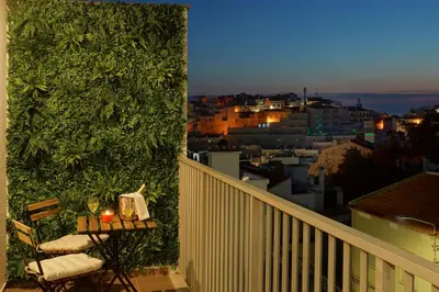 a balcony with a table and a green wall at RoofTop OldTown Residence in Albufeira