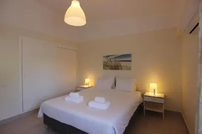 a bedroom with a white bed with two towels on it at Lago Azul Apartment I in Quarteira