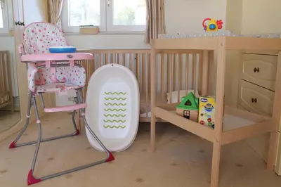 a childs room with a crib and a table and a chair at Villa Santa Barbara by Portucasa in Bordeira