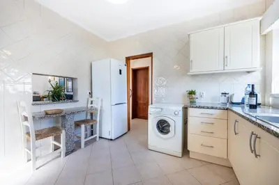 a kitchen with a white refrigerator and a dishwasher at Villa dos Netos in Albufeira