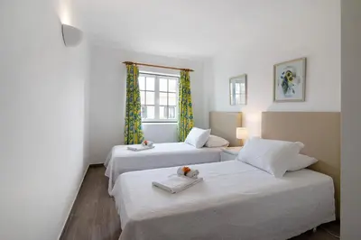 two beds in a room with white walls and a window at Apartamento Old Village T2 Duplex in Quarteira