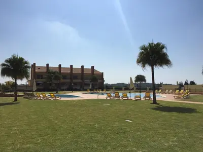 a resort with a pool and chairs and palm trees at Millennium Plaza in Vilamoura