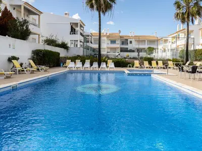 a large swimming pool with chairs in a resort at Akisol Albufeira Water in Albufeira