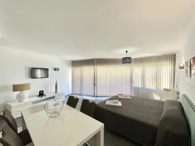 a bedroom with a bed and a table and a room at Ténis Studio Apartment - Vilamoura in Vilamoura