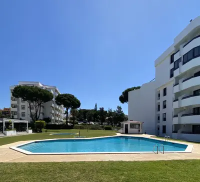 a swimming pool in front of a building at Ténis Studio Apartment - Vilamoura in Vilamoura