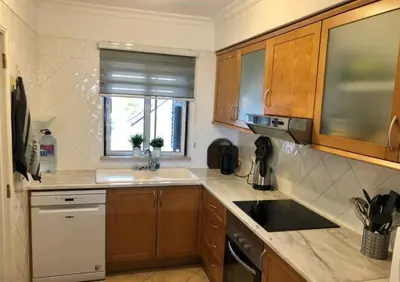 a kitchen with wooden cabinets and a sink and a window at Casa Sophie Albufeira in Albufeira