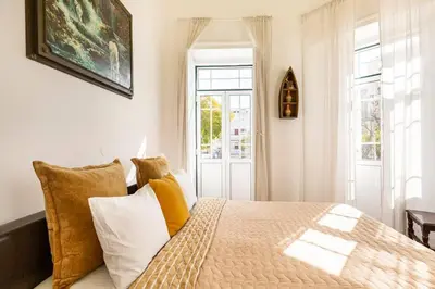 a bedroom with a bed with yellow and white pillows at Ti Maria Guest House in Faro